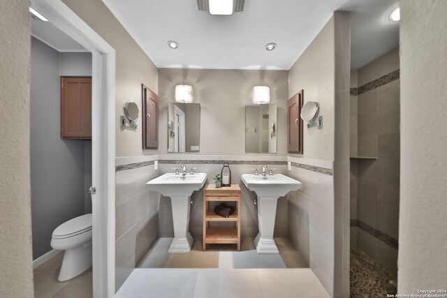 bathroom with backsplash, a tile shower, tile patterned flooring, tile walls, and toilet