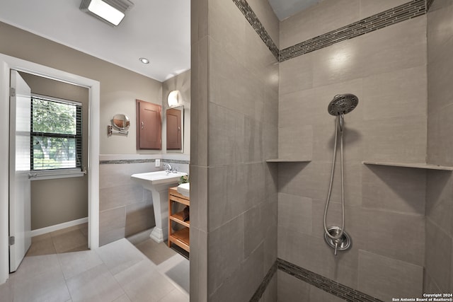 bathroom featuring tile patterned flooring, tile walls, a tile shower, and sink