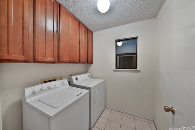 laundry room featuring a textured ceiling, light tile patterned flooring, separate washer and dryer, and cabinets