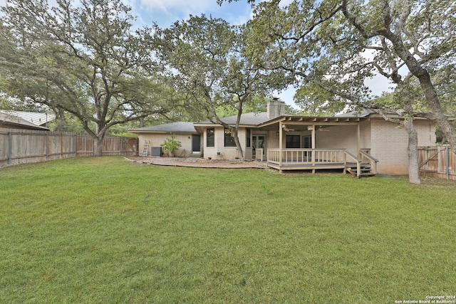 back of property with a deck and a yard