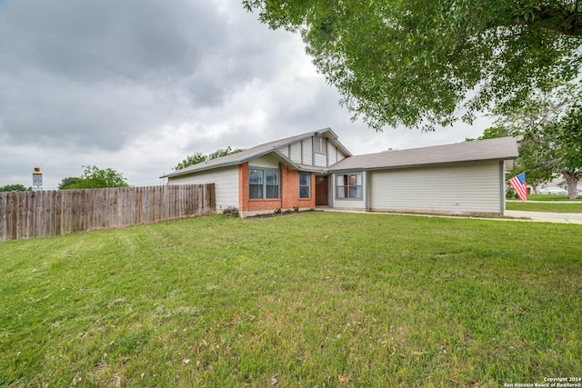 view of front of home with brick siding, a front lawn, and fence