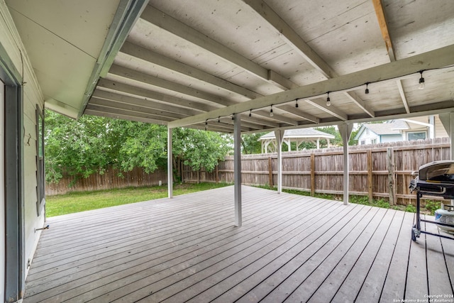 wooden deck with grilling area, a lawn, and a fenced backyard