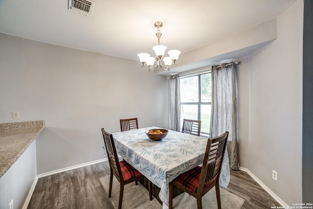 dining space featuring a chandelier, visible vents, baseboards, and wood finished floors