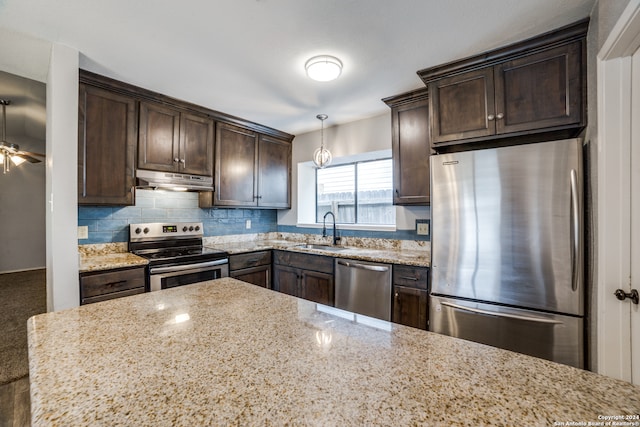 kitchen with appliances with stainless steel finishes, decorative backsplash, sink, light stone countertops, and ceiling fan