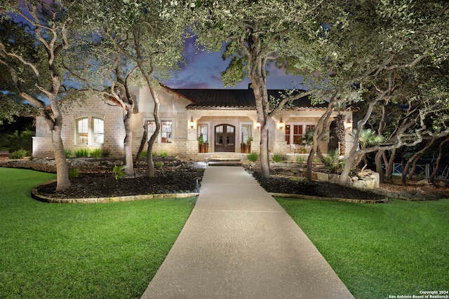 mediterranean / spanish house with french doors and a front lawn