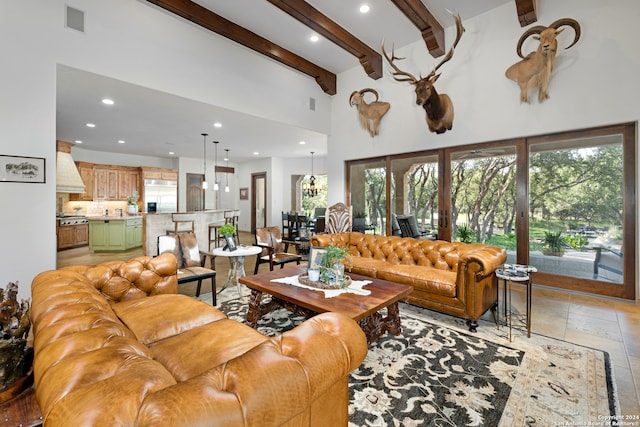 living room featuring a towering ceiling, beamed ceiling, a healthy amount of sunlight, and light tile patterned floors