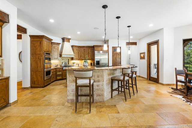 kitchen with custom exhaust hood, light stone counters, light tile patterned floors, and appliances with stainless steel finishes