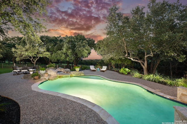 pool at dusk featuring a patio