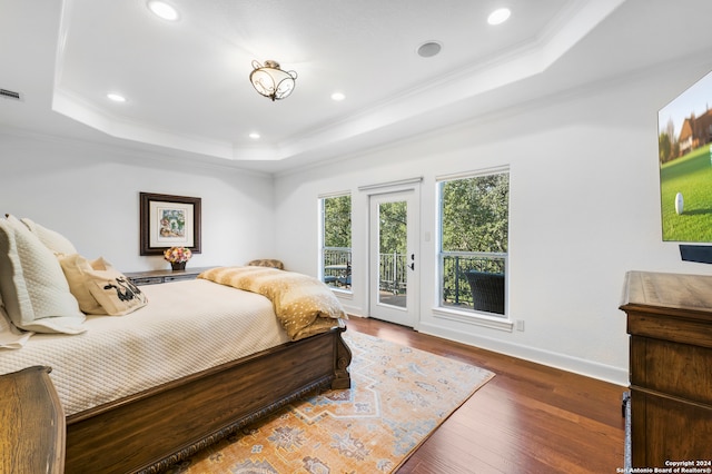 bedroom featuring a tray ceiling, dark hardwood / wood-style floors, access to exterior, and ornamental molding