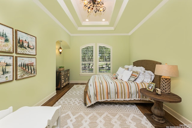 bedroom with a tray ceiling, ornamental molding, a chandelier, and dark hardwood / wood-style flooring