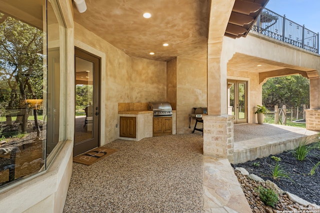 view of patio featuring a balcony, grilling area, french doors, and an outdoor kitchen