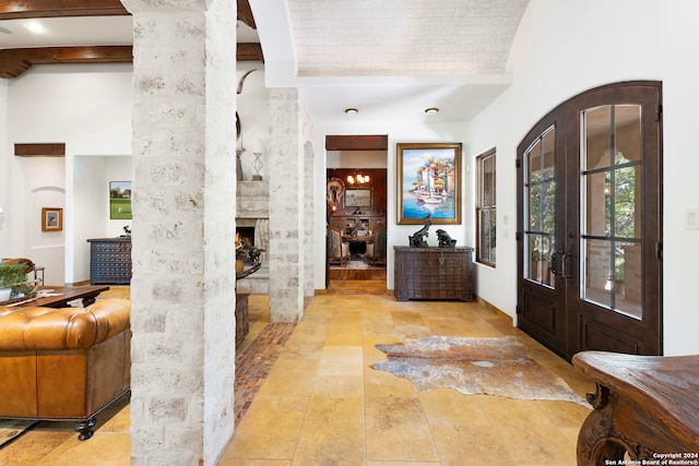 tiled foyer featuring a towering ceiling, decorative columns, and french doors