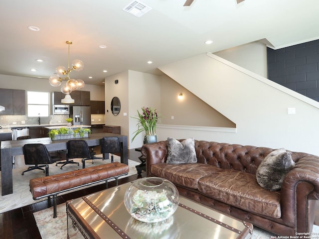 living room with wood-type flooring, an inviting chandelier, and sink