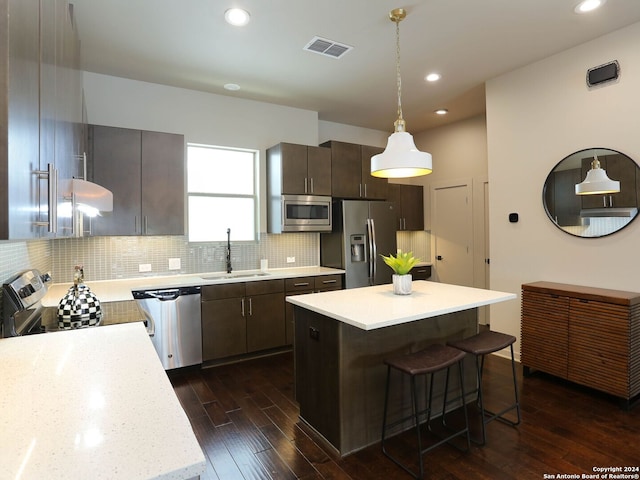 kitchen featuring tasteful backsplash, stainless steel appliances, dark hardwood / wood-style flooring, a center island, and hanging light fixtures