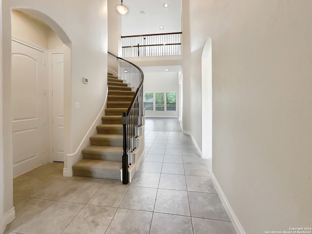 staircase with a high ceiling and tile patterned floors