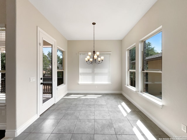 unfurnished dining area with light tile patterned floors, a wealth of natural light, and an inviting chandelier