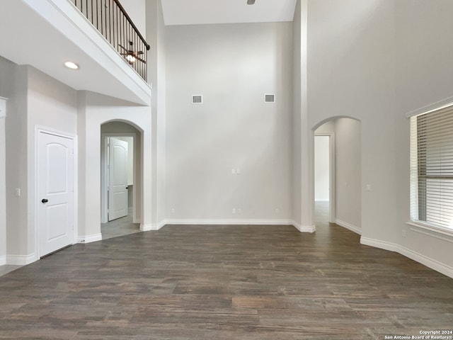 unfurnished living room featuring dark hardwood / wood-style floors and a towering ceiling