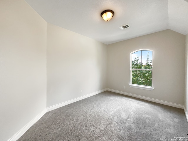 carpeted spare room featuring lofted ceiling