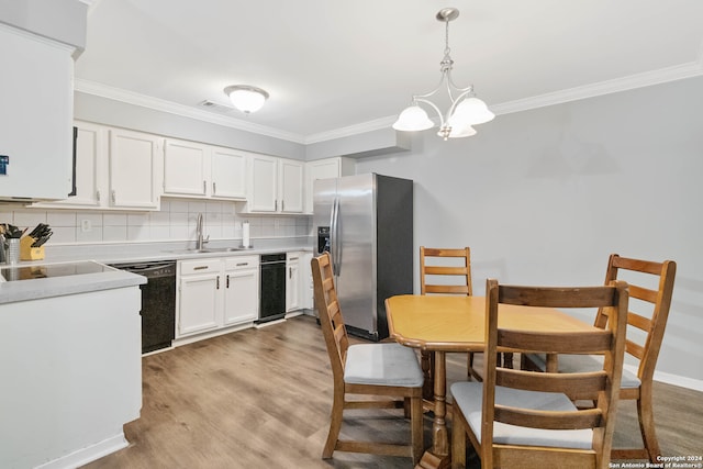 kitchen with black dishwasher, sink, stainless steel fridge, white cabinetry, and pendant lighting