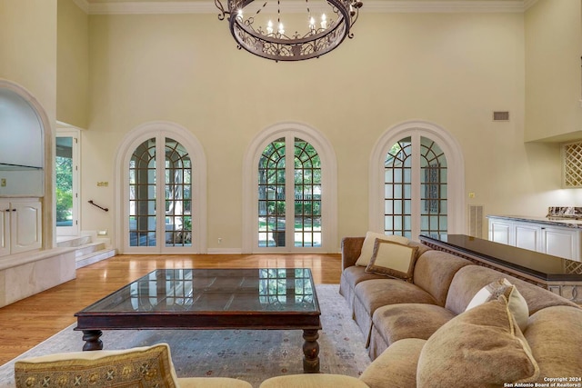 living room featuring ornamental molding, plenty of natural light, a chandelier, and light hardwood / wood-style floors