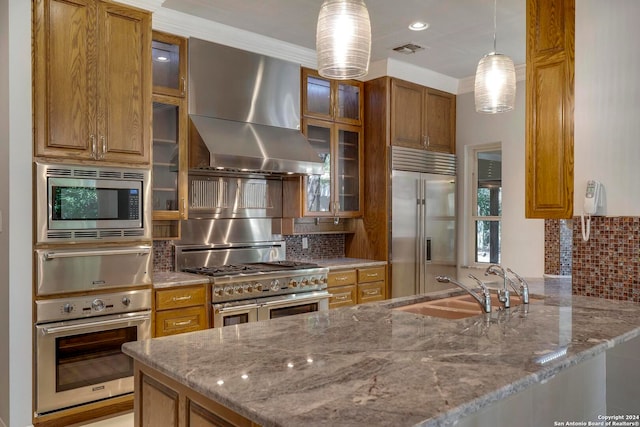 kitchen with built in appliances, light stone countertops, wall chimney exhaust hood, and kitchen peninsula