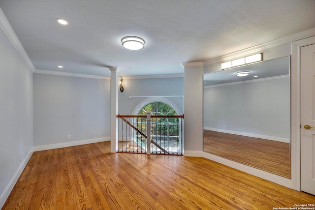 spare room with ornamental molding, a textured ceiling, and hardwood / wood-style flooring