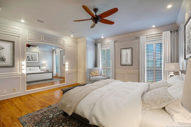 bedroom with ornamental molding, multiple windows, hardwood / wood-style floors, and ceiling fan