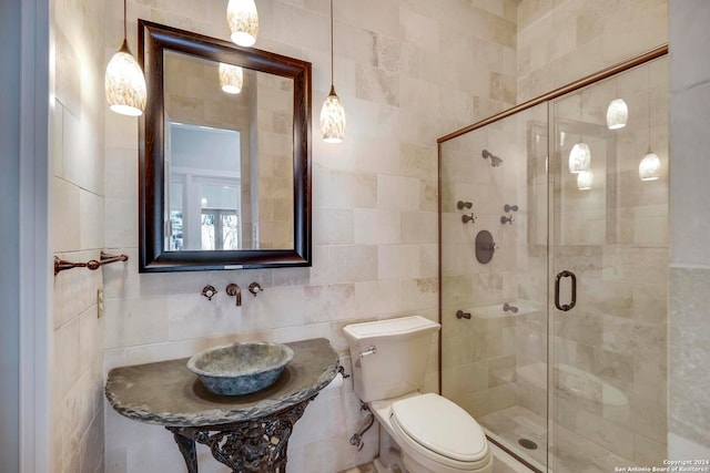 bathroom with tile walls, toilet, and an enclosed shower