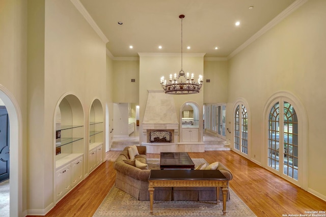 living room with a fireplace, ornamental molding, light hardwood / wood-style flooring, and a high ceiling