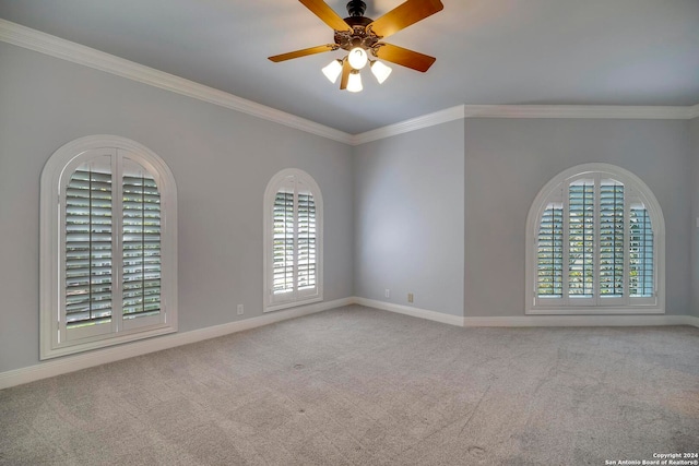 carpeted empty room featuring ceiling fan, plenty of natural light, and ornamental molding