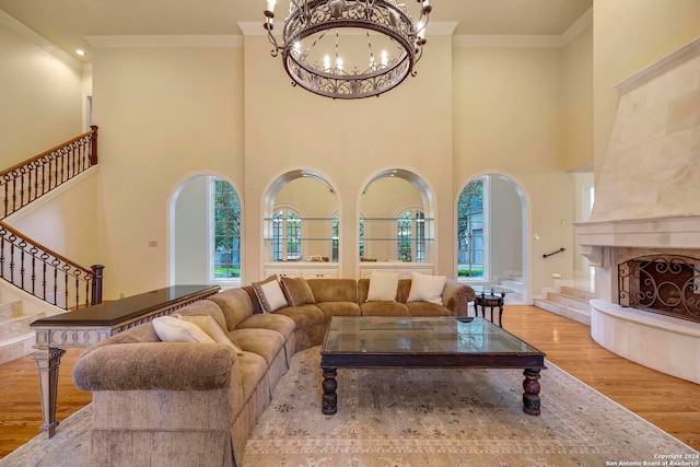 living room with a fireplace, crown molding, a notable chandelier, and light hardwood / wood-style floors