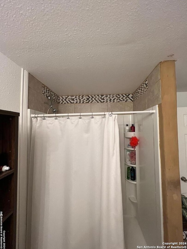 bathroom featuring curtained shower and a textured ceiling