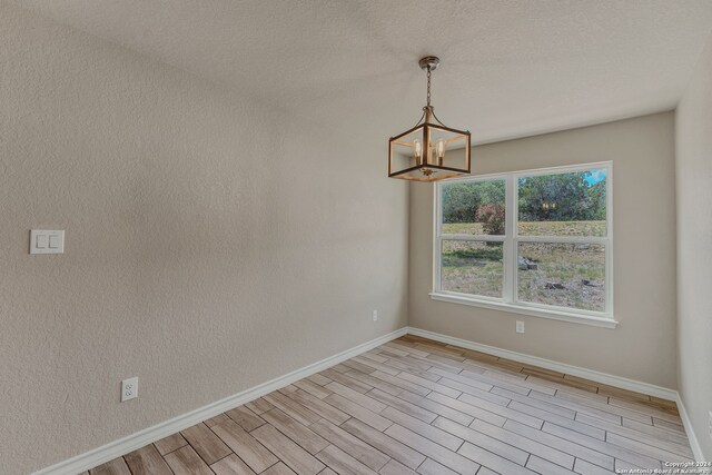 spare room featuring light hardwood / wood-style flooring and a notable chandelier