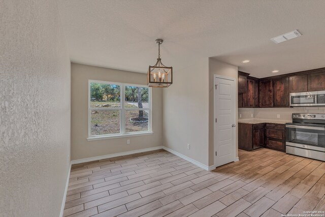 kitchen with decorative light fixtures, a textured ceiling, a notable chandelier, dark brown cabinetry, and stainless steel appliances