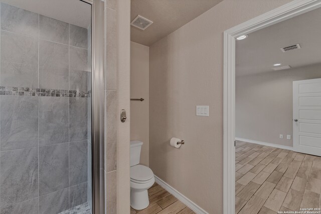 bathroom featuring toilet and a shower with shower door