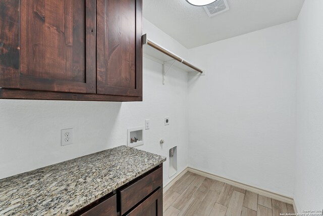 laundry area featuring hookup for an electric dryer, washer hookup, light wood-type flooring, and cabinets