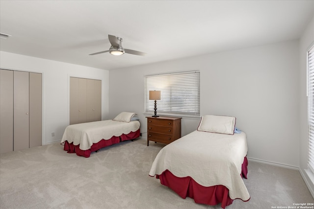 carpeted bedroom with ceiling fan and two closets