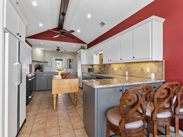 kitchen featuring a breakfast bar, sink, range, white refrigerator, and kitchen peninsula