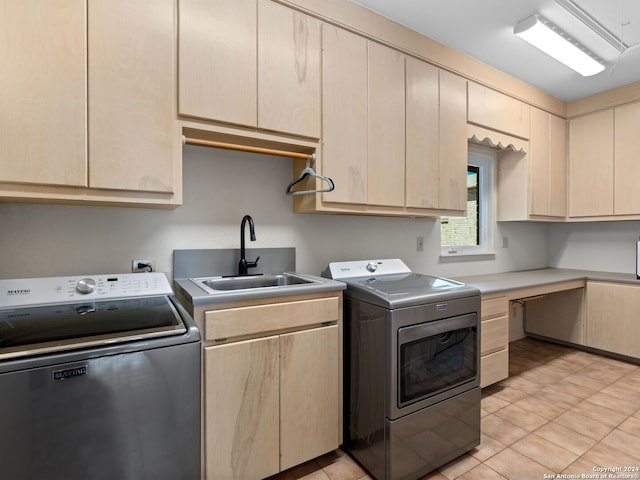 laundry area with washer and dryer, sink, light tile patterned floors, and cabinets