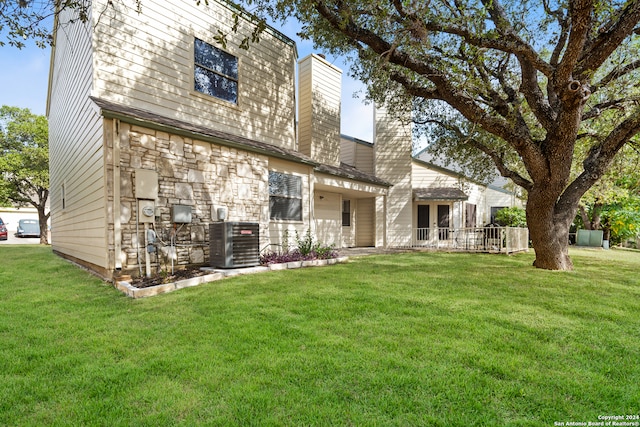 back of property with a lawn and central AC