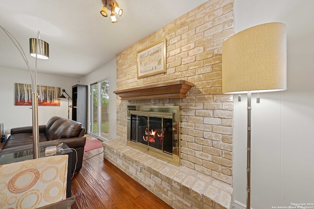 living room featuring a textured ceiling, brick wall, dark hardwood / wood-style flooring, and a fireplace