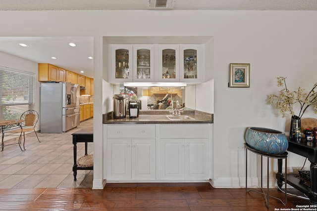 bar with stainless steel fridge with ice dispenser, light brown cabinetry, hardwood / wood-style flooring, and sink