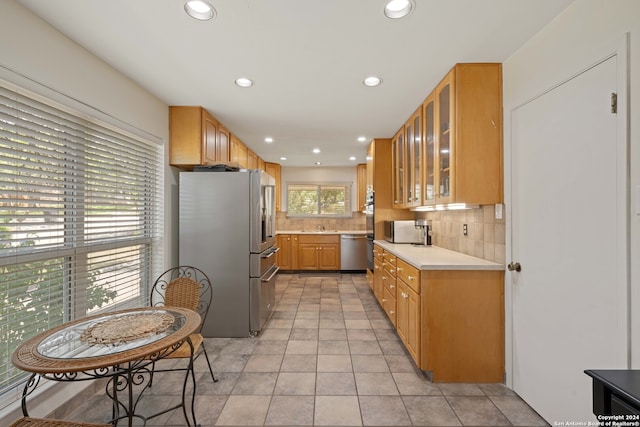 kitchen featuring stainless steel appliances, light tile patterned floors, and backsplash