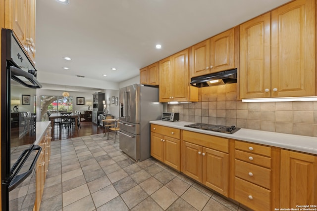 kitchen featuring black double oven, light hardwood / wood-style flooring, gas stovetop, high end fridge, and tasteful backsplash