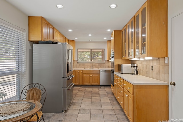 kitchen with sink, light tile patterned flooring, stainless steel appliances, and decorative backsplash