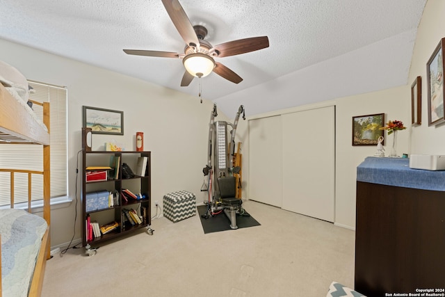 workout room featuring a textured ceiling, ceiling fan, and light carpet