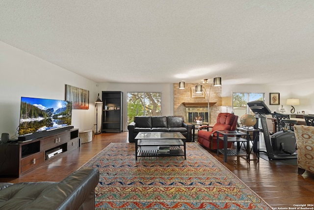 living room with a textured ceiling, dark wood-type flooring, and a brick fireplace