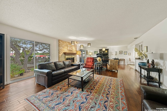 living room with a textured ceiling, brick wall, dark hardwood / wood-style floors, and a brick fireplace