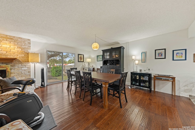 dining space featuring a textured ceiling, a large fireplace, and dark hardwood / wood-style flooring