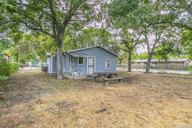 rear view of house featuring cooling unit, fence, and stucco siding